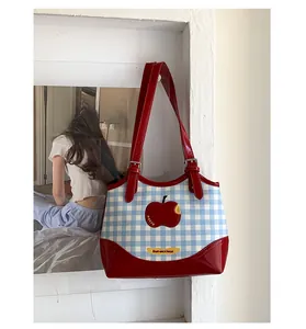 Close-up of red apple embroidery and Not Anxious label on blue checkered canvas bag