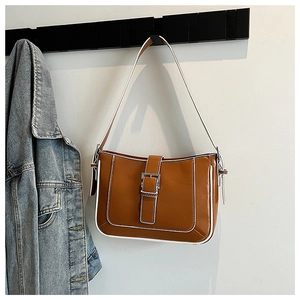 Close-up of vintage brown shoulder bag with white piping and metallic buckle detail