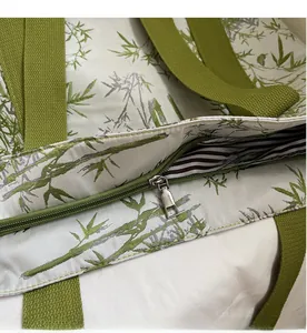 Detail view of a green bamboo pattern tote bag with a smooth silver zipper and striped lining