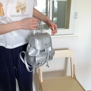 Detailed shot of silver textured leather mini backpack with dual front pockets and drawstring