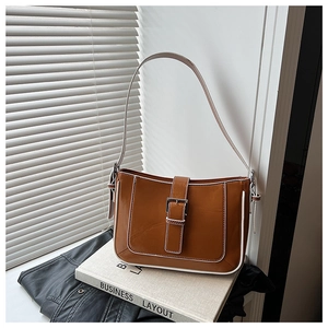 Detailed close-up of brown crescent bag with white contrast stitching and metal buckle