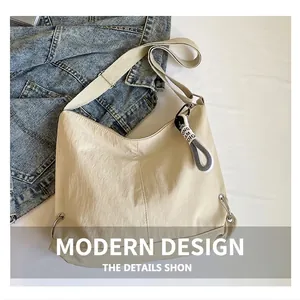 Détail d'un sac hobo en nylon beige avec sangle en tissu, anneau métal et ruban lettré