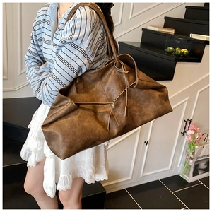 Close-up of a large vintage brown leather tote bag with thin straps and minimalist design