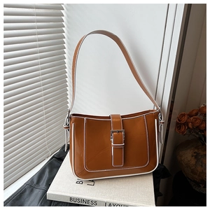 Close-up of caramel crescent bag with white contrast piping and silver metallic buckle