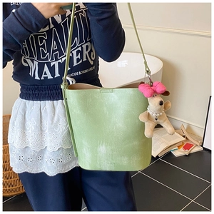 Light green leather bucket bag with puppy plush pendant and pink bow detail
