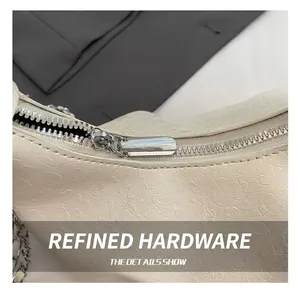 Close-up of silver metal zipper detail on white embossed leather dumplings crossbody bag