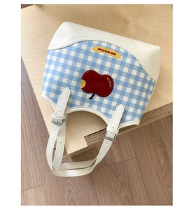 Detail of blue plaid tote bag with red apple patch and adjustable white shoulder strap