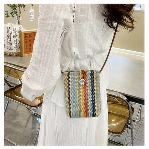Detailed shot of rainbow striped woven crossbody mini bag with brown shoulder strap