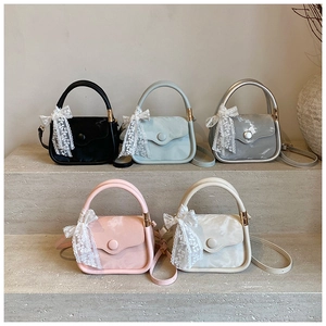Detailed row of satin handbags in five colors featuring lace bow charms and shoulder straps