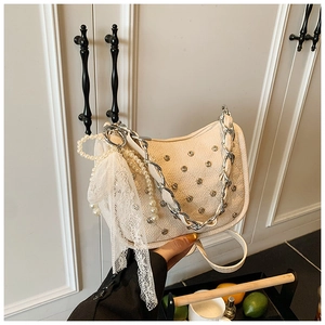 Détail du sac matelassé crème avec clous argentés, perles et nœud en dentelle élégant