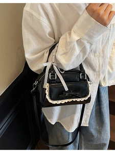 Black patent leather bow handbag with blue ribbon detail and adjustable shoulder strap