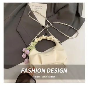 Detail of cream crescent dumpling bag with silver chain and purple tulip pendant