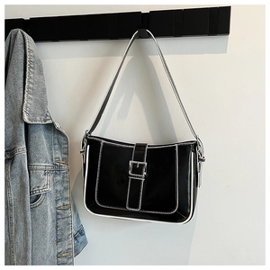 Detail of black crescent shoulder bag with white stitching and silver buckle hanging