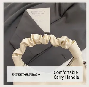 Detail of cream ruched handle and smooth leather texture on stylish dumpling bag