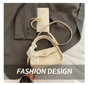 Close-up of off-white crossbody bag featuring elegant lace ribbon and golden hardware