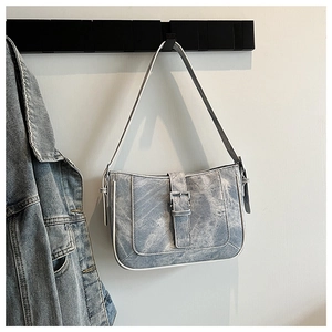 Detail of light blue denim shoulder bag with silver square buckle and contrast edging