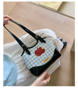 Detail of blue gingham tote bag with apple embroidery and adjustable black leather strap