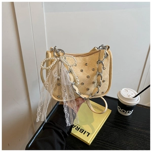 Détail du sac tressé beige avec rivets, chaîne en métal et nœud en perles