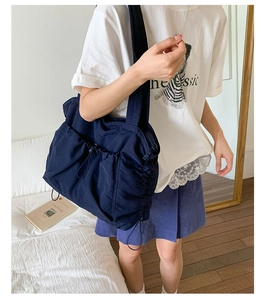 Detail der dunkelblauen Nylon-Tote mit Kordelzugfalten und Außentasche am Modell