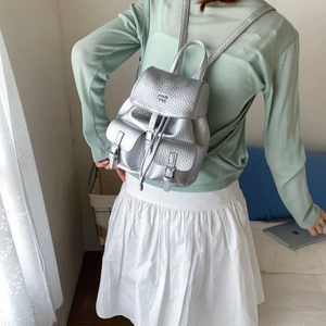 Detail view of silver textured leather mini backpack with metal finish and drawstrings