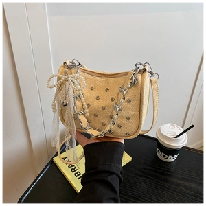 Détail du sac tissé jaune avec chaîne argentée et pendentif noeud en dentelle