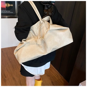 Side view of beige soft leather tote bag on model showing large capacity and drape