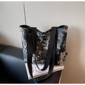 Detail of black tote bag featuring white bamboo print and wide fabric shoulder straps
