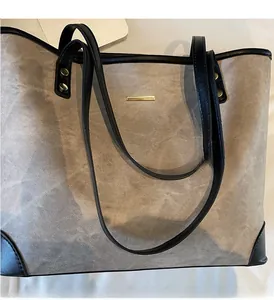 Detail of taupe tote bag showing reinforced black leather handles and gold rivet accents