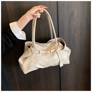 Detailed close-up of cream leather tote bag featuring pleated texture and buckle detail