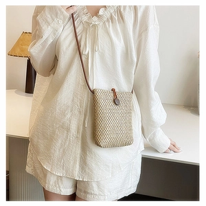 Detailed macro of handmade woven straw mini bag showing wood buckle and natural fiber texture