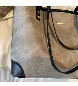 Detail of washed fabric texture and black leather strap on a large grey tote bag