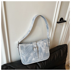 Close-up of light blue denim texture shoulder bag with white piping and silver buckle