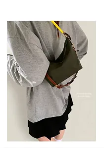 Détail du sac croissant en nylon vert foncé avec bandoulière en cuir et chaîne