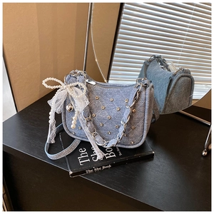 Détail du sac en jean bleu clair avec matelassage en strass et nœud en dentelle sur un livre