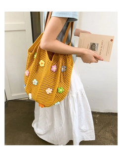 Detail of yellow knit tote bag featuring colorful 3D crochet flowers and brown leather handles