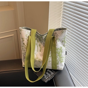 Detail of floral canvas tote bag showing green bamboo print and wide woven straps