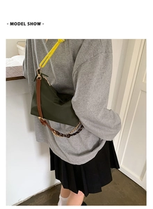 Sac baguette en nylon vert foncé avec bandoulière en cuir porté par un mannequin