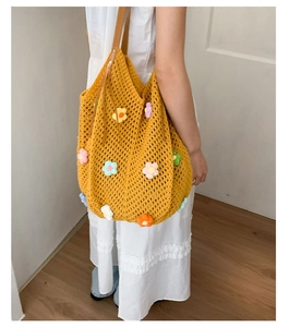 Detailed knit texture of yellow crochet bag with vibrant 3D flower charms and leather strap