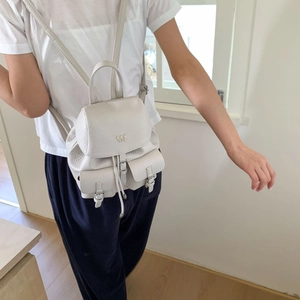Detailed back view of a compact cream lychee leather backpack worn by a model