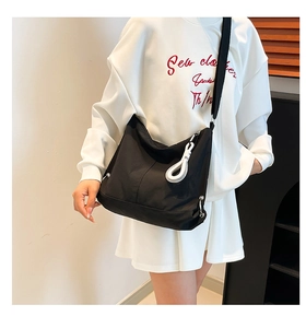 Détail du sac dumpling en nylon noir avec cordons blancs et languette décorative
