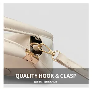 Close-up of premium light gold metal hook and leather strap on cream square handbag