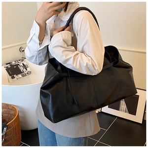 Black large PU leather tote bag shoulder carry view on model in a minimalist room