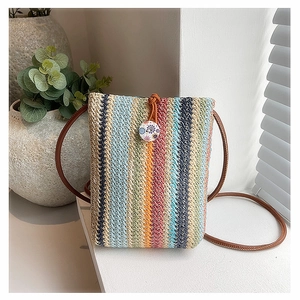 Detail of colorful rainbow straw woven mini bag with floral button and leather strap