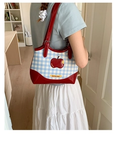 Detail of blue plaid tote bag featuring red apple embroidery and Not Anxious label