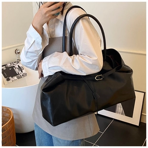 Close-up of the fine leather texture and metallic buckle on a black tote bag
