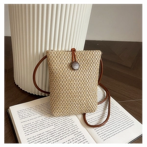 Close-up of rainbow straw woven mini bag detail with button closure on vintage book