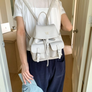 Detail of off-white lychee leather backpack with silver buckles and drawstring closure