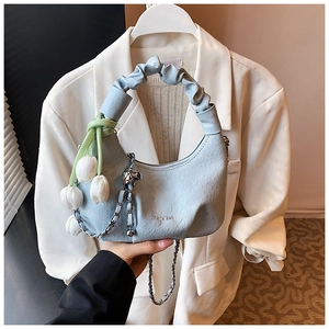 Detail of light blue hobo bag with scrunchie handle, tulip charm and metal chain