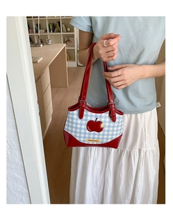 Close-up of blue plaid tote bag featuring a red apple pattern and red patent leather handles