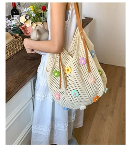 Detail view of a white crochet tote bag with colorful 3D floral accents and leather straps